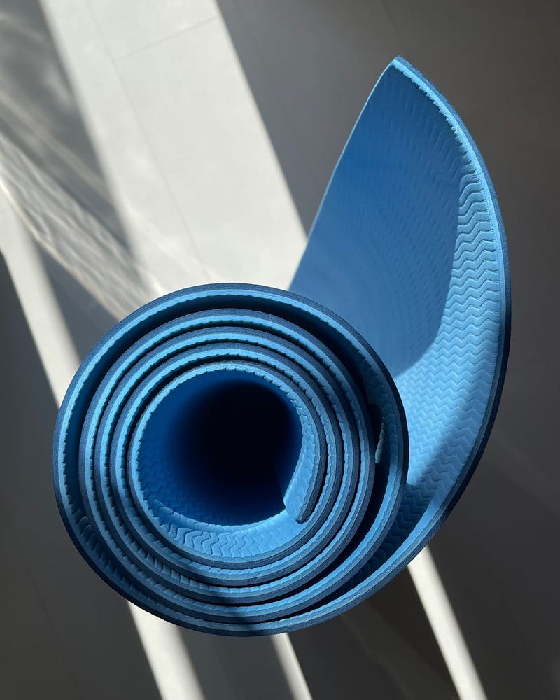 A bright and clean living room space prepared for a home workout, with a yoga mat on the floor.