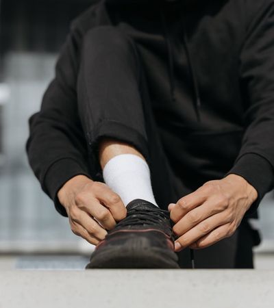 Close-up of a person's feet in sneakers on a mat, ready to start exercising.